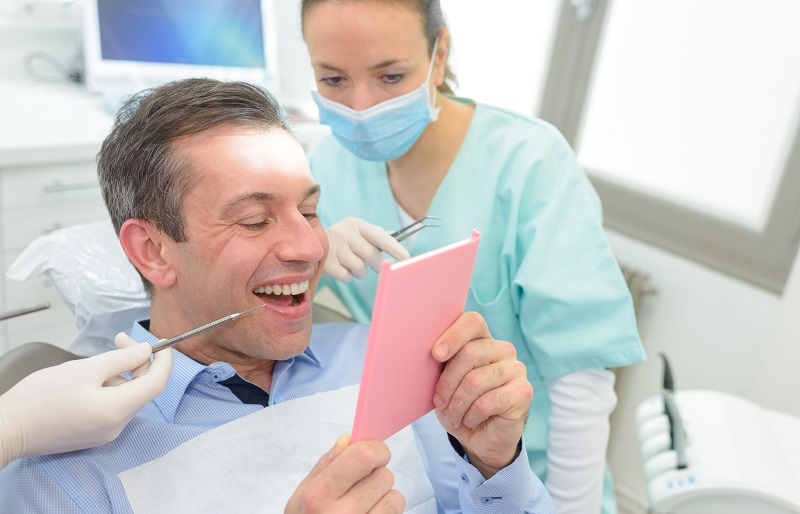 Patient examining teeth in a mirror after a dentist visit
